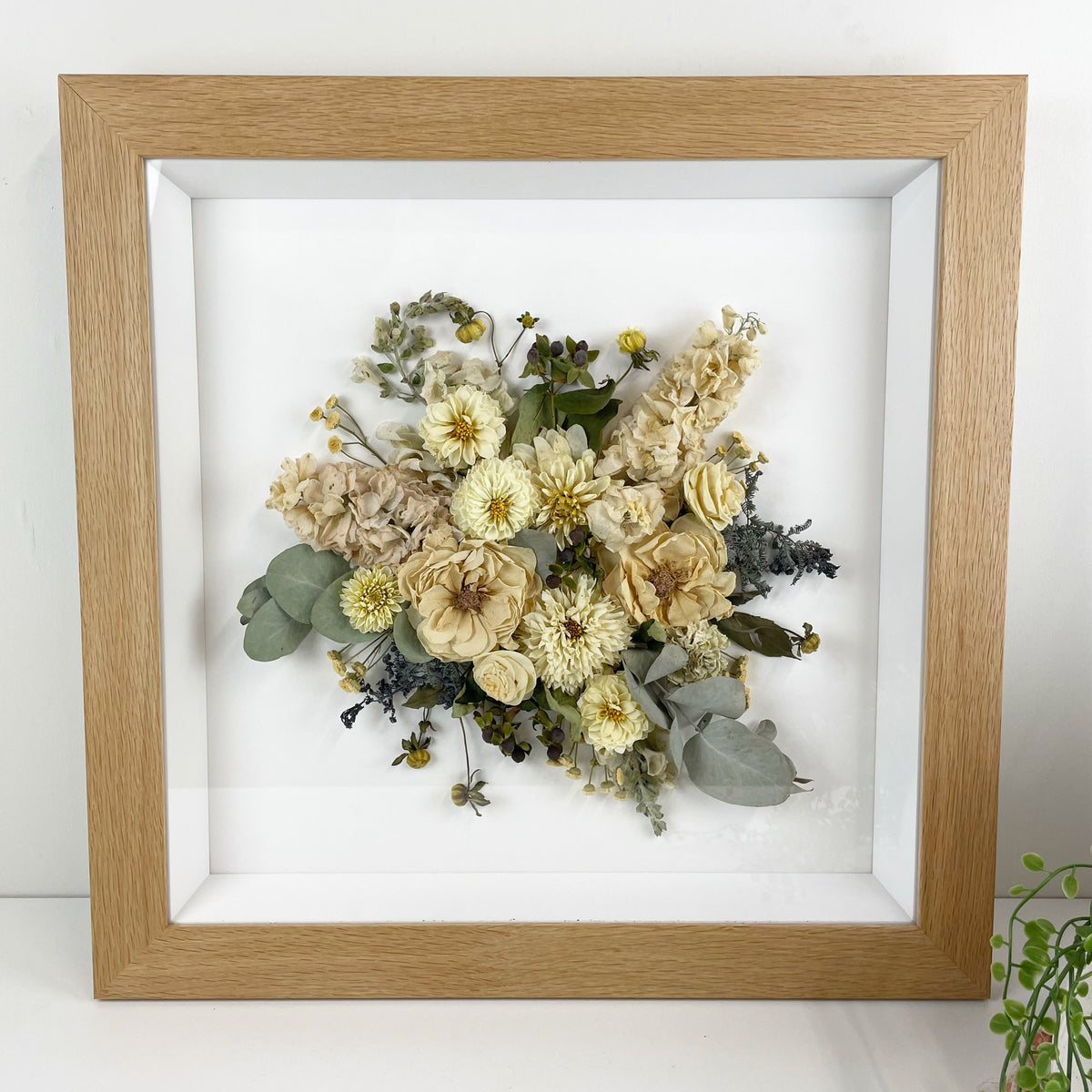 A wooden shadow box with a 400 x 400 mm opening, containing a bouquet of dried flowers arranged neatly within it.