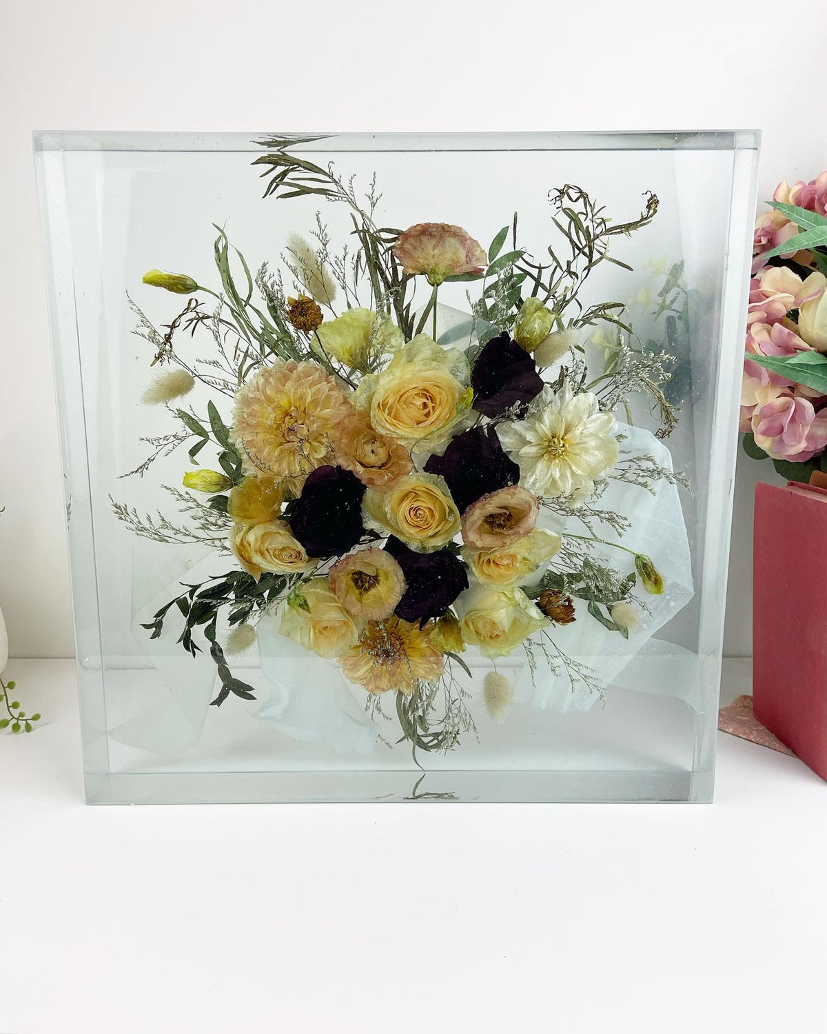 Resin block with a gold cream and dark red bouquet arranged inside it.