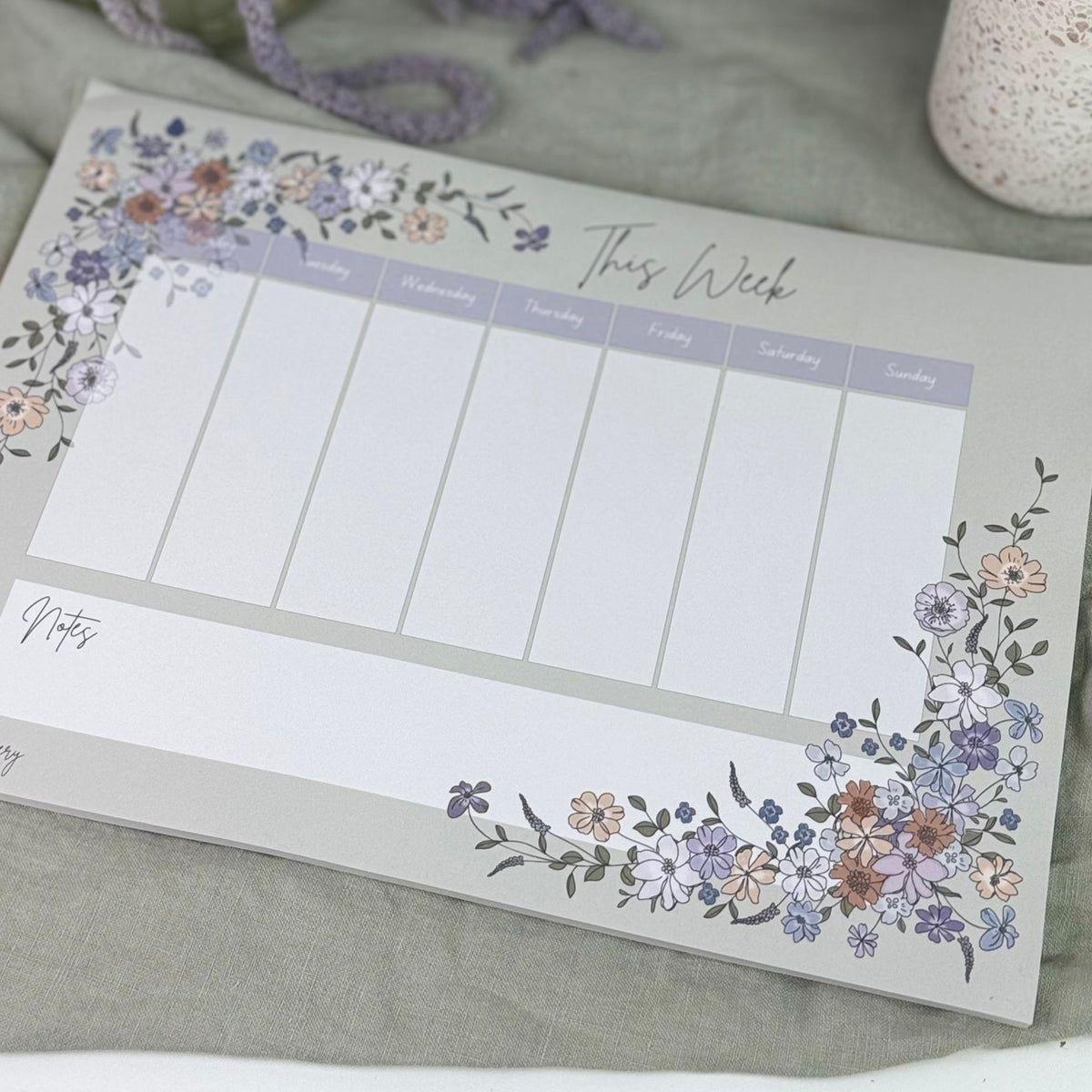 Floral-themed notepad with a pen holder and flowers on a light surface